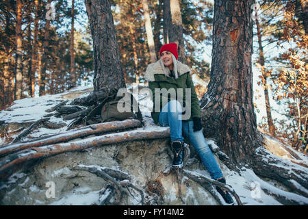 Voller Länge jungen Frau sitzen im Schnee bedeckt Wald Stockfoto