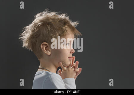 Nahaufnahme eines nachdenklichen jungen mit Hand am Kinn vor grauem Hintergrund Stockfoto