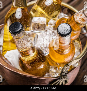 Kalte Flaschen Bier in den ehernen Eimer auf dem Holztisch. Stockfoto