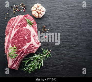 Rib-Eye Steak mit Gewürzen auf dem schwarzen Hintergrund. Stockfoto