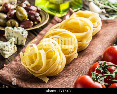 Pasta Zutaten. Cherry-Tomaten, Spaghetti Nudeln, Rosmarin und Gewürze auf dem Holztisch. Stockfoto