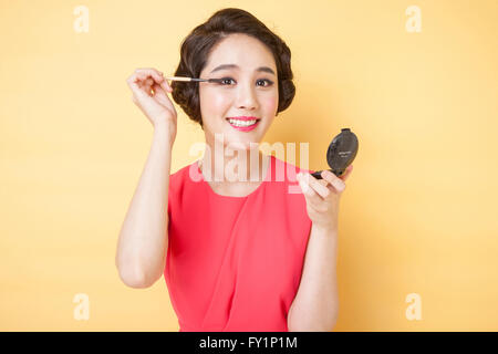 Porträt des jungen lächelnde Frau im retro-Stil setzen auf Mascara starrte auf Vorderseite Stockfoto
