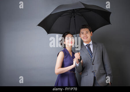 Junge Paar in Retro-Styles teilen einen Regenschirm starrte auf Vorderseite lächelnd Stockfoto