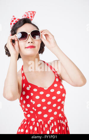 Porträt des jungen lächelnde Frau im retro-Stil tragen und Sonnenbrille starrte vorne berühren Stockfoto
