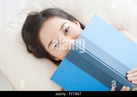 Porträt des jungen lächelnde Frau liegend ein Buch lesen Stockfoto