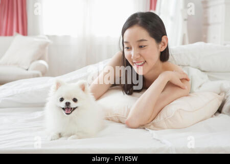 Porträt der jungen lächelnde Frau liegen verdeckt im Bett, Blick auf ihre Welpen Stockfoto
