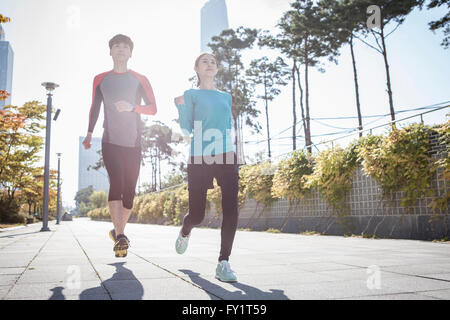 Junge, lächelnde paar Joggen im park Stockfoto