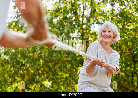 Beautiful senior Woman spielen Tauziehen mit ihrem Ehemann im Sommer Stockfoto