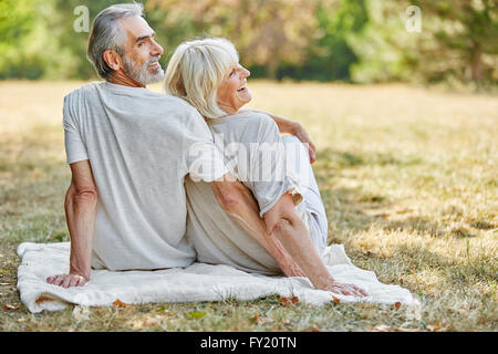 Gerne älteres paar sitzen und Lächeln auf einer Decke im Garten im Sommer Stockfoto