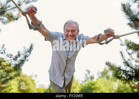 Alte Mann geht auf Krücken in der Reha in der Natur Stockfoto