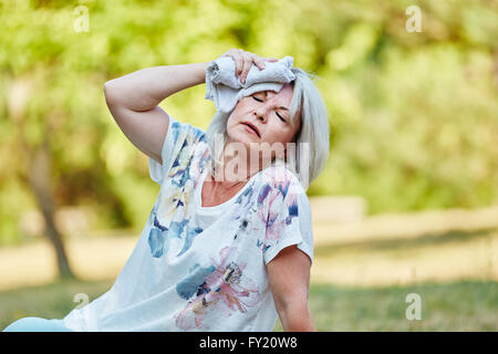 Senior Ohnmacht Frau hält nassen Lappen auf der Stirn abkühlen lassen Stockfoto