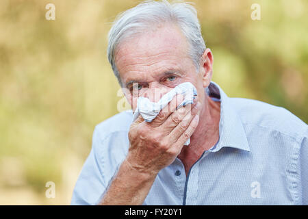 Ältere Mann mit Heuschnupfen mit einem Gewebe in der Natur Stockfoto