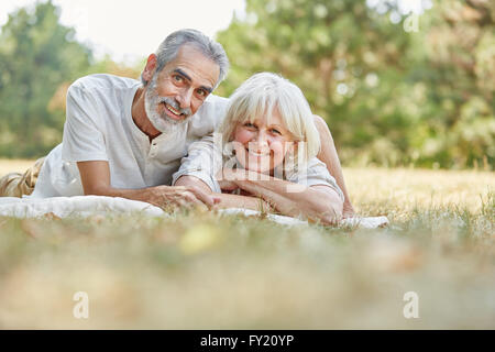 Älteres Paar in der Liebe legen glücklich auf die Gras im Sommer Stockfoto