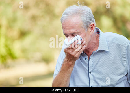 Alter Mann mit einer Erkältung mit einem Gewebe in der Natur Stockfoto