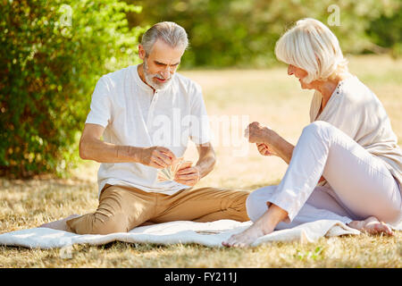 Älteres Paar spielen eines Karte Spiel Wettbewerbs im Garten im Sommer Stockfoto