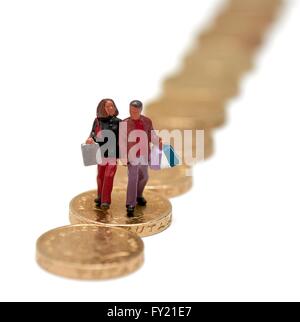 Ein Miniatur-paar Einkaufstaschen zu Fuß über die Pfund-Münzen Stockfoto