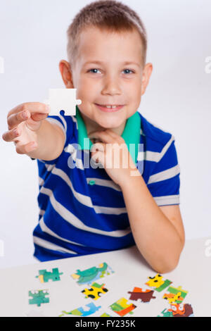 Niedlichen kleinen Jungen spielen Rätsel am Tisch Stockfoto