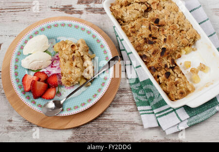 Apple crumble Dessert mit Erdbeeren und Vanillecreme auf rustikalen hölzernen Hintergrund Stockfoto