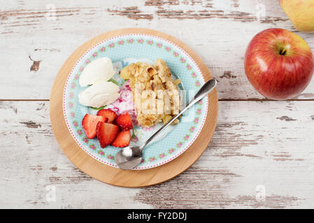 Apple crumble Dessert mit Erdbeeren und Vanillecreme auf rustikalen hölzernen Hintergrund Stockfoto