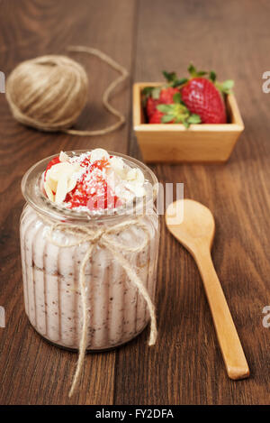 Chia-Samen-Pudding mit Erdbeeren, Bananen, Mandeln und Kokosnuss. Dunklem Holz Stockfoto