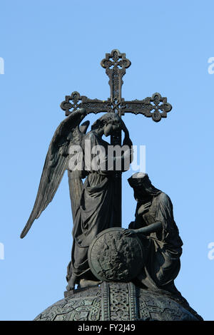 Statue von ein Engel mit einem Kreuz und einem knelling Frau Russland vertreten überstieg das Denkmal für die Millennium von Russland (1862) Der russische Bildhauer Michail Mikeshin in Weliki Nowgorod, Russland vorgesehen. Stockfoto