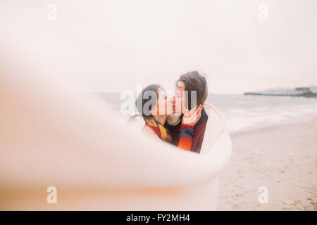 Schöne junge Brautpaar schauen liebevoll einander in weißen Decke gehüllt. Winter-Meer im Hintergrund Stockfoto