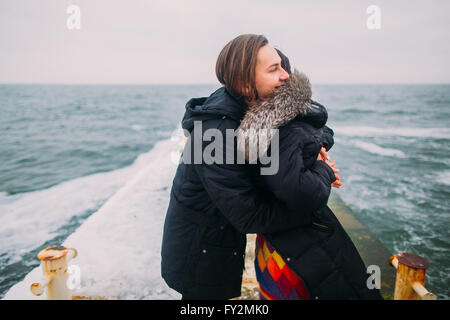 Schöne junge Paar zärtlich umarmt auf stoned Pier während regnerischen Herbsttag. Winter-Meer-Hintergrund Stockfoto