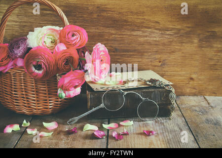 altes Buch und Brille neben schönen Wiesenblumen auf Holztisch. Jahrgang gefiltert. Stockfoto