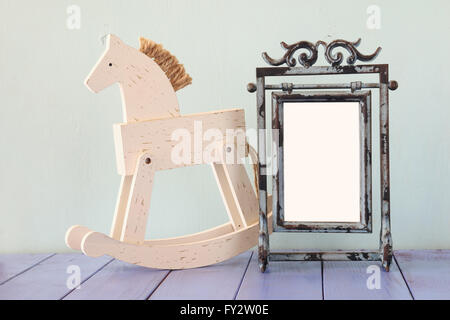 Antike leer Vintage-Stil-Rahmen und alte Schaukelpferd über Holztisch. Stockfoto