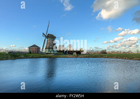 Schöne alte holländische Windmühle bei bewölktem Himmel im Wasser reflektiert Stockfoto