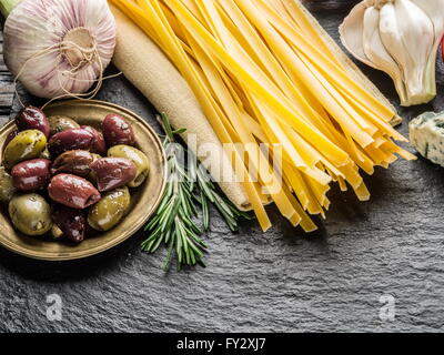 Pasta Zutaten. Cherry-Tomaten, Spaghetti Nudeln, Rosmarin und Gewürze auf einem Graphit-Brett. Stockfoto