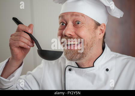 Weißen männlichen Koch in der Küche mit einer Schöpfkelle Stockfoto