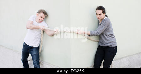 Wütend Paar ziehen ein Seil von den gegenüberliegenden Seiten der Ecke des Hauses, konzeptionelle Bild der Konflikt in der Beziehung Stockfoto