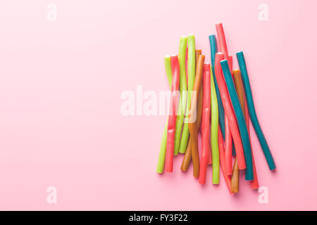 Süße Gummibärchen-Sticks mit unterschiedlichen Geschmack. Draufsicht der leckeren Süßigkeiten auf rosa Hintergrund. Stockfoto