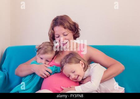 Schwangere Frau umarmt seine kleinen Töchter. Selektiven Fokus. Stockfoto