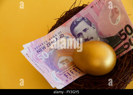 Neuseeland-Dollar und ein goldenes Ei in einem Nest. Stockfoto