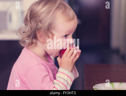 Lustige kleine Mädchen (2 Jahre) Essen Sie einen Pfirsich. Selektiven Fokus. Stockfoto