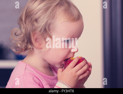 Lustige kleine Mädchen (2 Jahre) Essen Sie einen Pfirsich. Selektiven Fokus. Stockfoto
