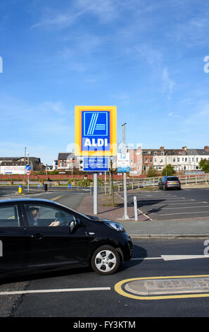 Ein Auto vorbei an dem Aldi-Schild am Eingang zum Parkplatz eines großen Aldi-Supermarkt in Blackpool, Lancashire, UK Stockfoto