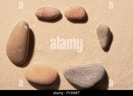 Rechteckiger Rahmen sechs kleine und große Meer Steine auf Sand. Sommer Strand Hintergrund. Ansicht von oben Stockfoto