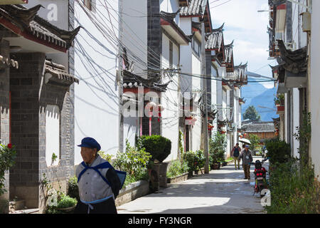 Die Menschen gehen über eine Straße inmitten chinesischer traditioneller Architektur in Shuhe, Lijiang alte Stadt in der Provinz Yunnan, China Stockfoto