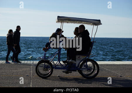 Familie Radfahren mit einem zweisitzigen Fahrrad auf Thessalonikis New promenade Bereich an einem sonnigen Nachmittag. Salonique, Nordgriechenland. Stockfoto