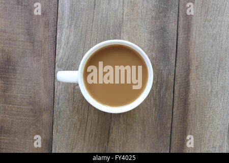 Weiße Kaffeetasse platziert auf dem alten Holzboden, Design für über Koffein trinken. Stockfoto