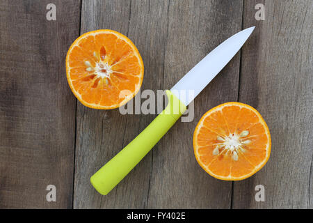 Mandarinen und Acryl Messer platziert auf dem alten Holzboden, Design-Konzept für über gesunde Lebensmittel. Stockfoto