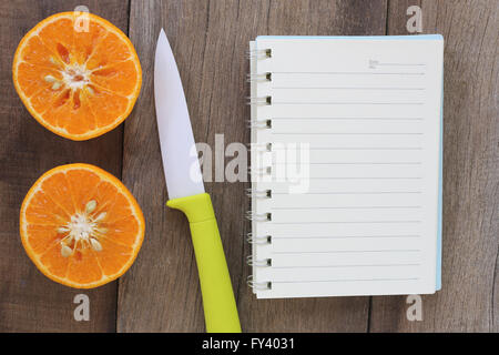 Mandarinen und Acryl Messer platziert auf dem alten Holzboden, Design-Konzept für über gesunde Lebensmittel. Stockfoto