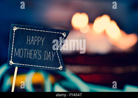 Nahaufnahme von einem Black Flag-förmigen Schild mit dem Text glücklichen Mütter Tag und eine Torte mit brennenden Kerzen im Hintergrund gekrönt Stockfoto