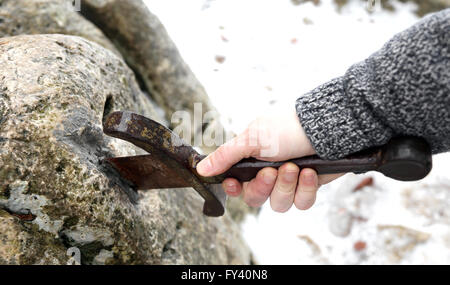 Hand des tapferen Ritters versucht, das magische Schwert Excalibur in den Stein zu entfernen Stockfoto