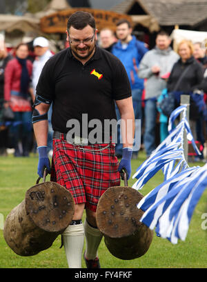 Mann trägt ein Protokoll in jeder Hand tragen rote Tartan Kilt, mit blauen und weißen schottischen Flaggen an seine Seite. Stockfoto