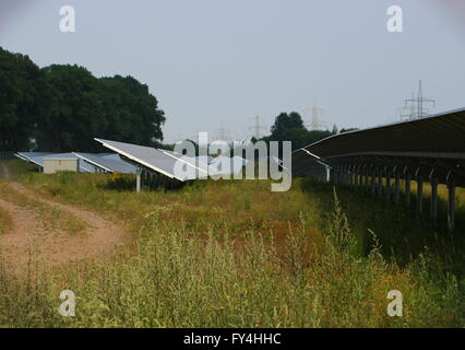 PV-Anlage außerhalb der Stadt mit Stromleitungen im Hintergrund. Stockfoto