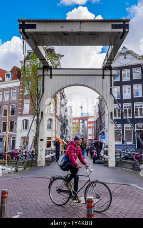 Eine freitragende Brücke in Amsterdam und ein Rad Fahrrad Bike Mann Junge Aalen in der Sonne im April Stockfoto